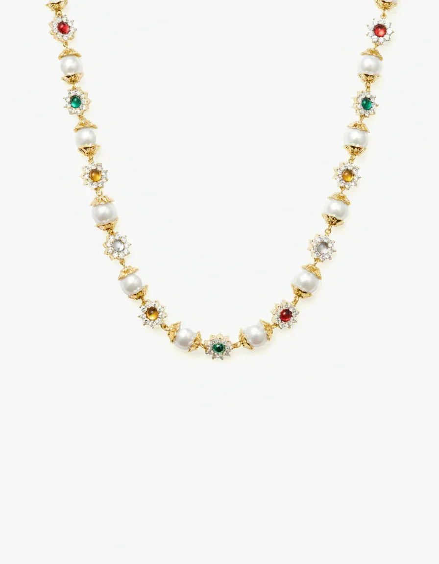 Gold necklace with alternating pearls and multicolored gemstone floral settings on white background