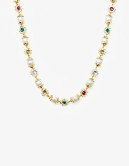 Gold necklace with alternating pearls and multicolored gemstone floral settings on white background