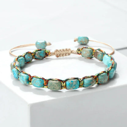Handwoven bracelet with blue turquoise stone beads and multicolor thread on a white surface