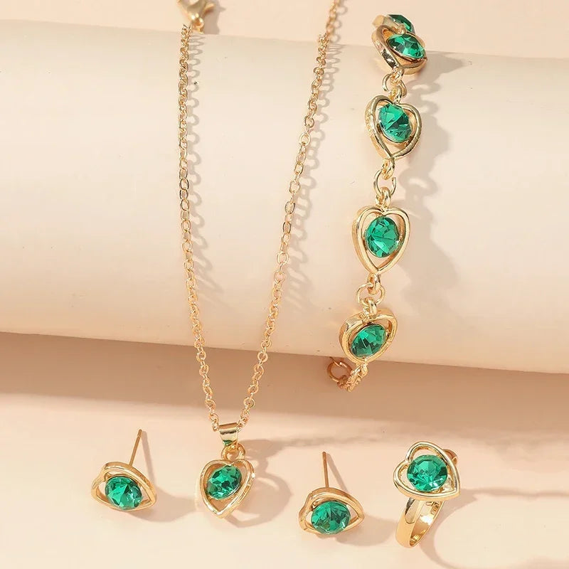 Gold jewelry set with green heart-shaped gemstones including necklace, bracelet, ring, and earrings