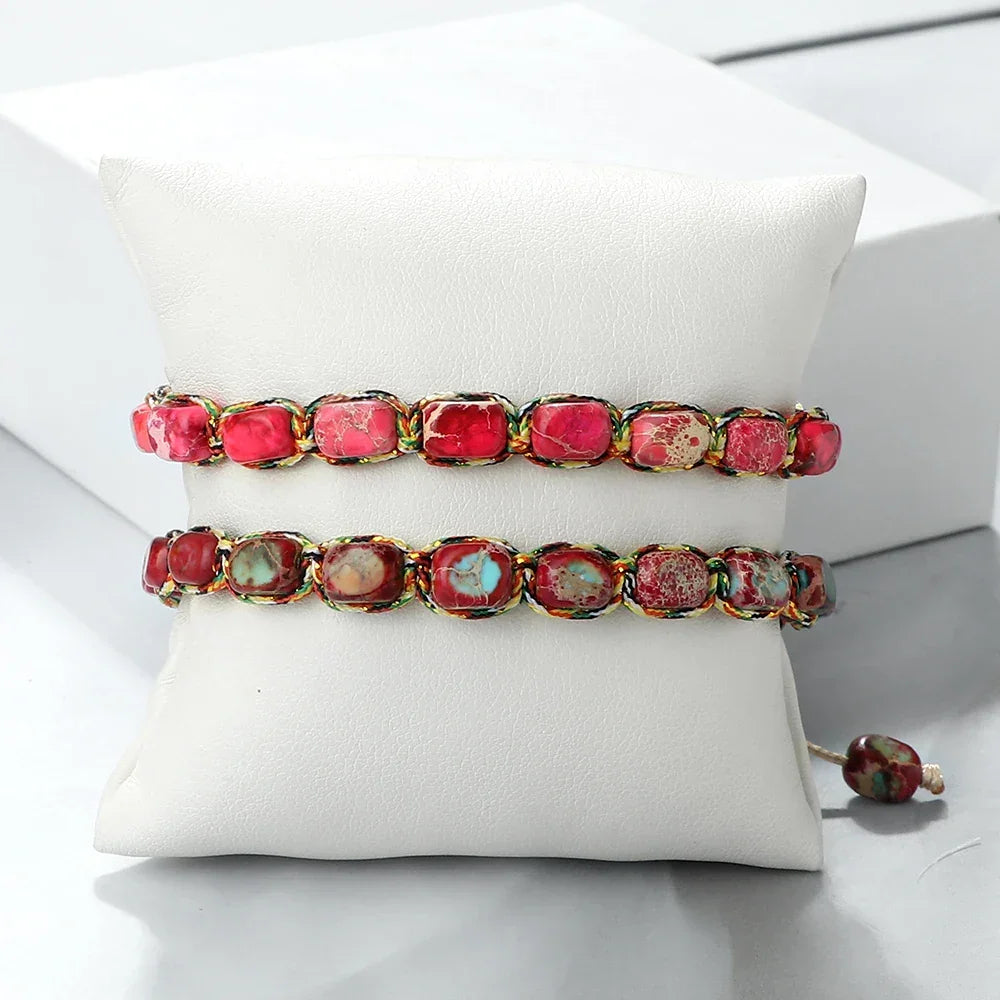 Two beaded bracelets with rectangular red and turquoise stones displayed on a white cushion