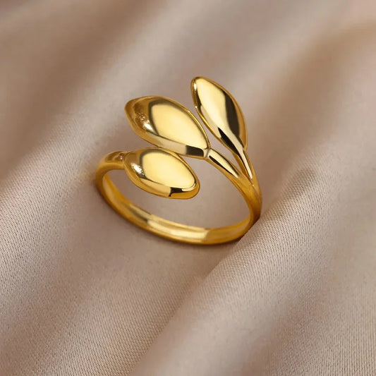 Elegant gold ring with three leaf-shaped elements on beige fabric background