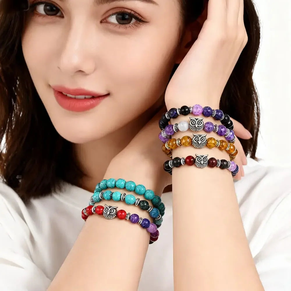 Woman wearing colorful beaded owl bracelets featuring purple, turquoise, red, black, and amber stones