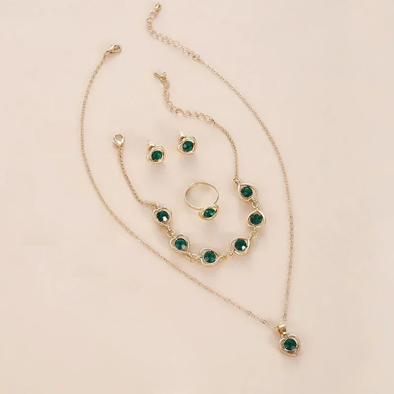 gold jewelry set with green gemstones including necklace, bracelet, ring, and earrings on beige background