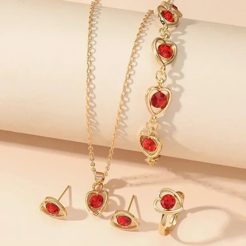 Gold heart-shaped jewelry set with red gemstones featuring necklace, bracelet, earrings, and ring